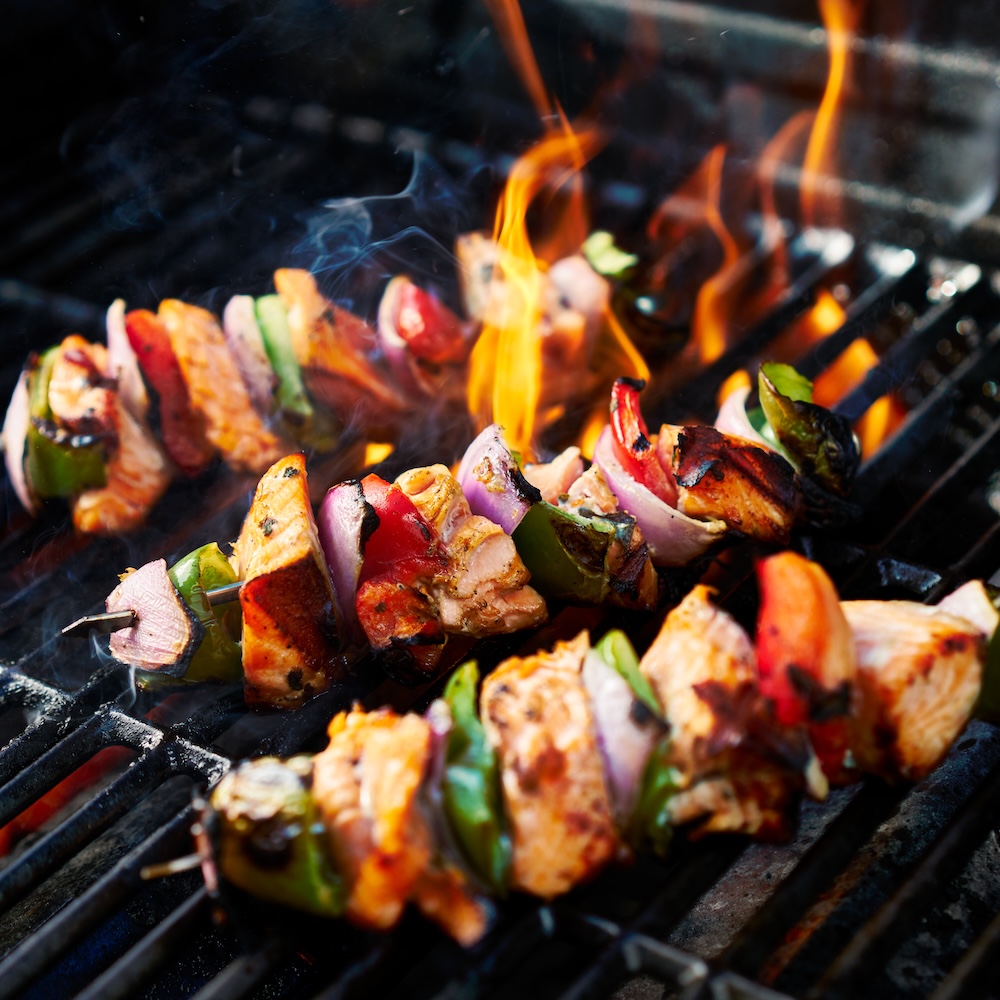 Grilled chicken kebobs on flaming grill